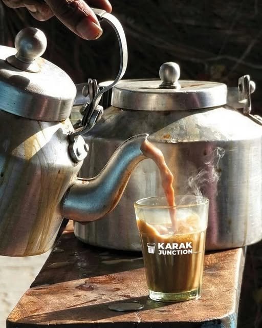 Traditional steel kettles pouring karak into a Karak Junction glass