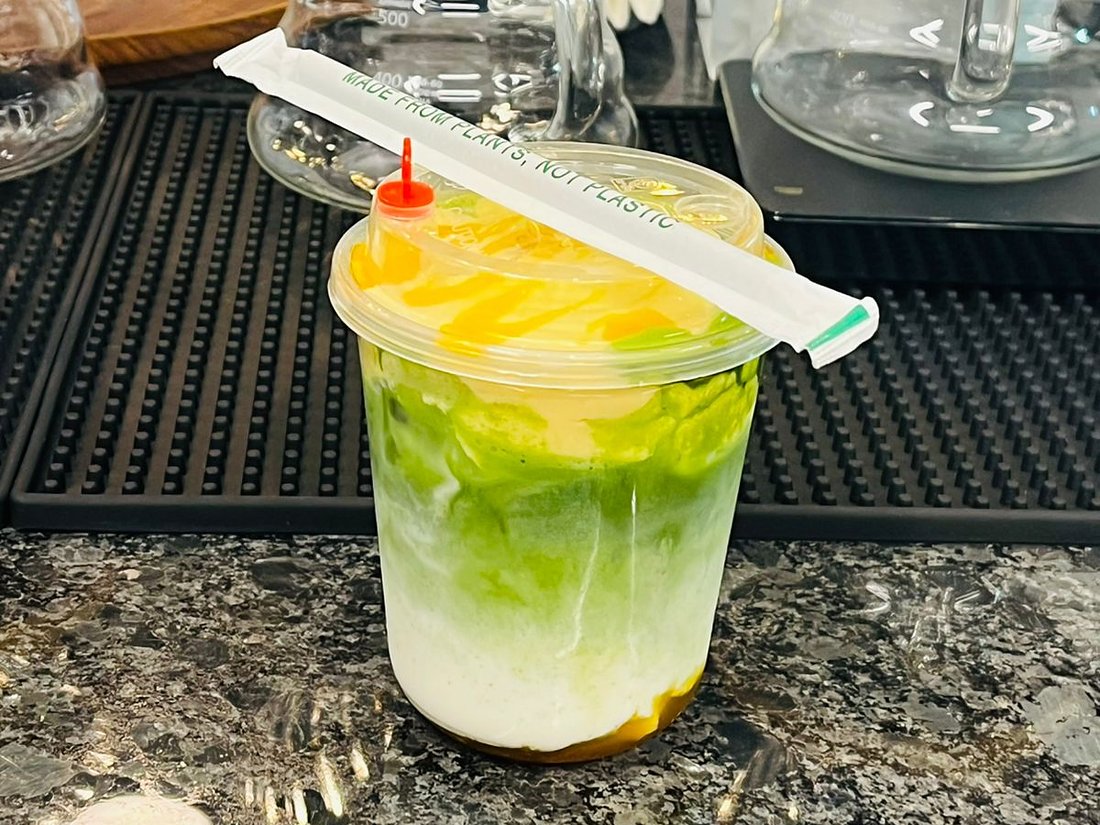 Layered mango matcha with a plant-based straw at Karak Junction