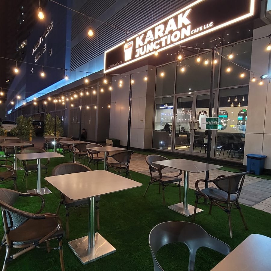 The terrace at night under string lights, sign glowing above